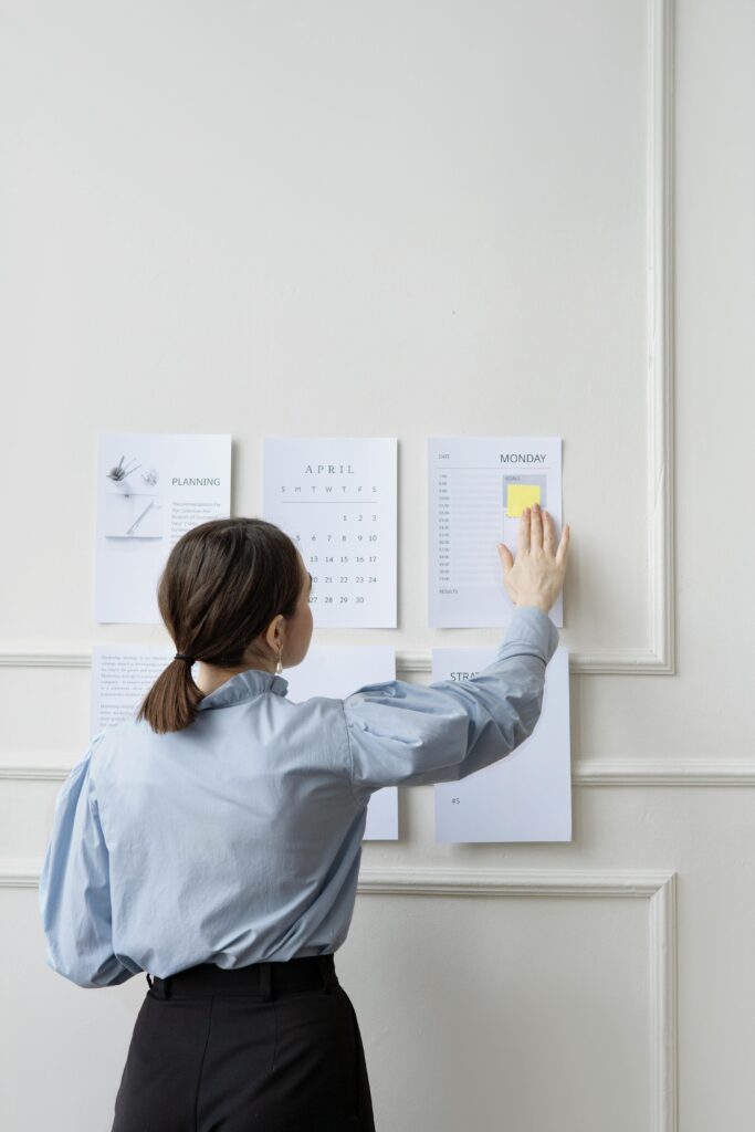 Woman organizing wall planner in office showing strategy and planning.